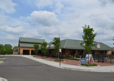Modern commercial buildings with green roofs under a cloudy sky.