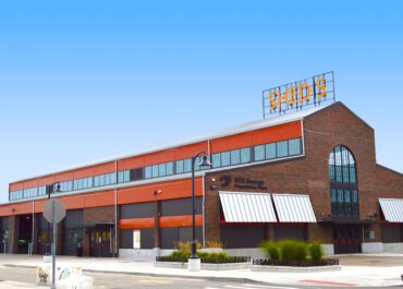 Modern red-brick commercial building with SHUDE sign on the roof.